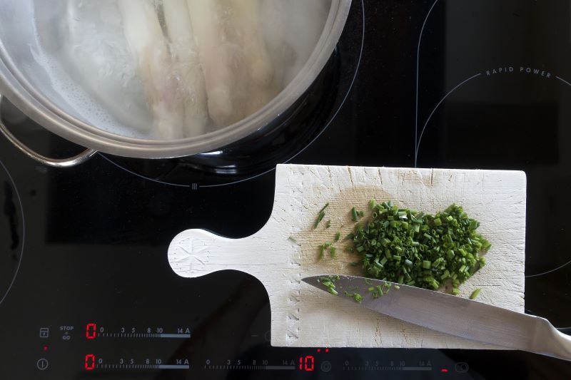 Kochfeld auf dem ein Topf und ein Schneidebrett mit Messer liegt Kochen auf Induktionskochfeld