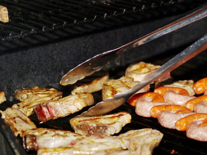 Eine Grillzange wendet Fleisch Eine Grillzange in Aktion veranschaulicht.