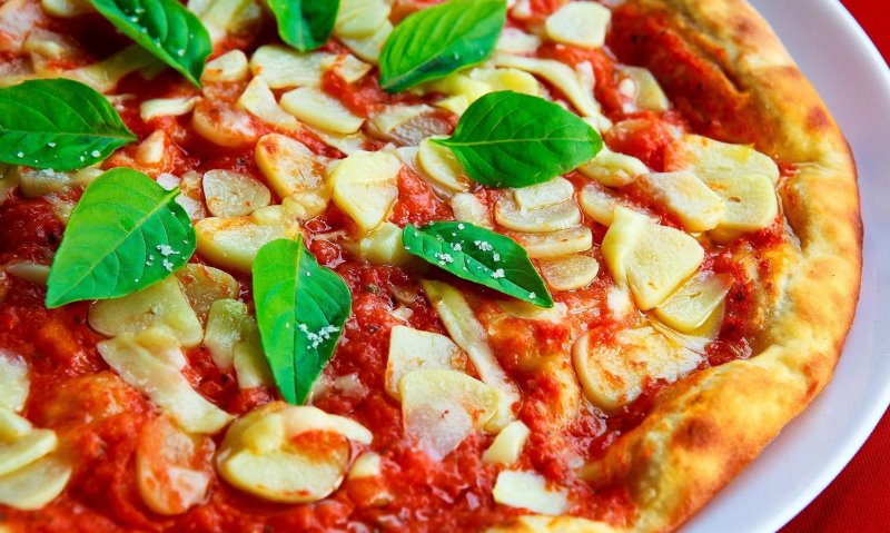 Pizza mit Knoblauchscheiben und Basilikum Pizza mit Knoblauchscheiben und Basilikum