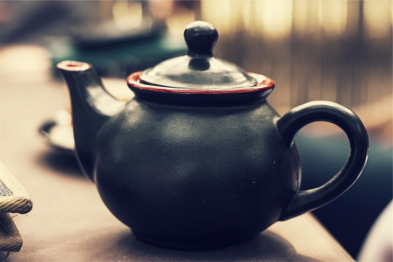 Schwarze Keramik-Teekanne liegt auf dem Tisch