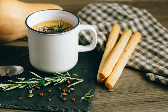 Suppentasse mit Kürbissuppe und Grissinis